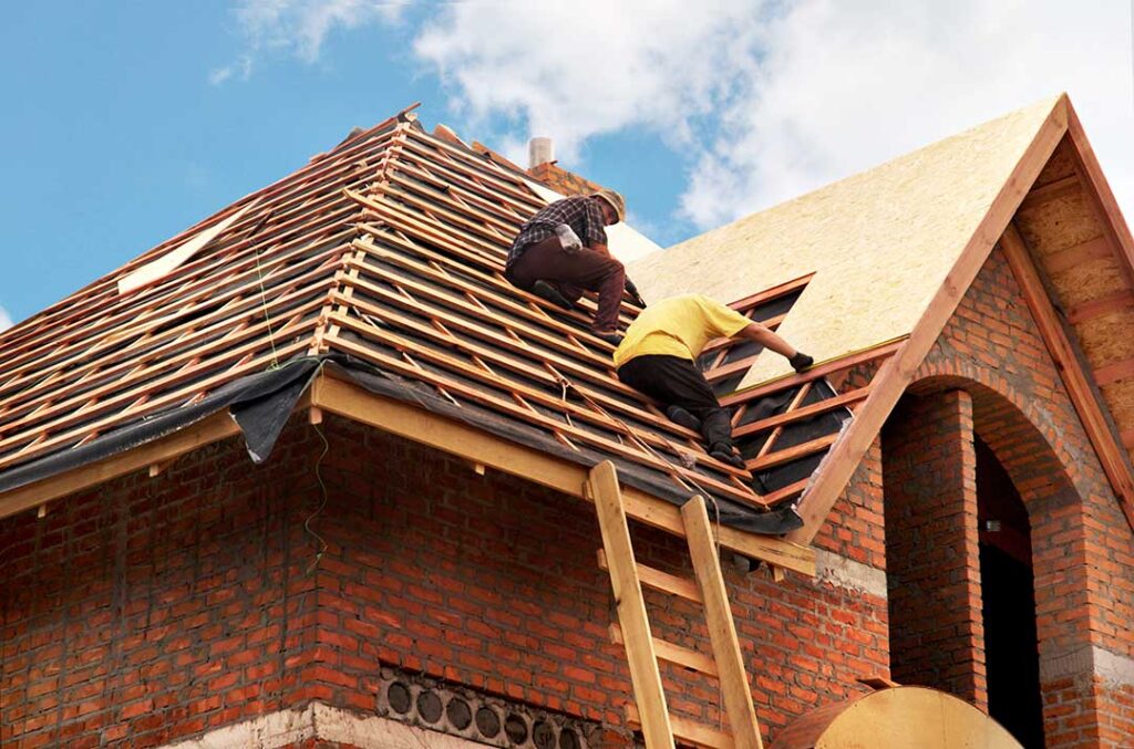 Homeowner inspecting roof shingles from the ground beside a ladder, gutters, and fallen leaves.