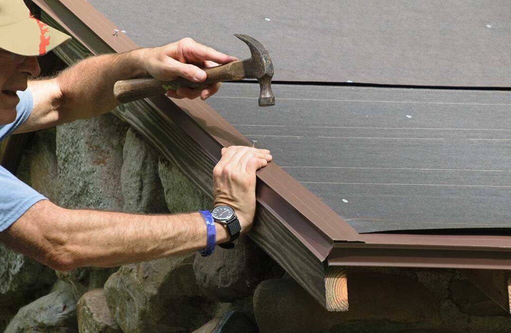 Homeowner examining attic insulation and roof framing beneath a snow-covered residential roof