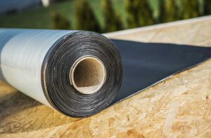 A homeowner examines attic insulation and roof vents beneath a sloped roof.